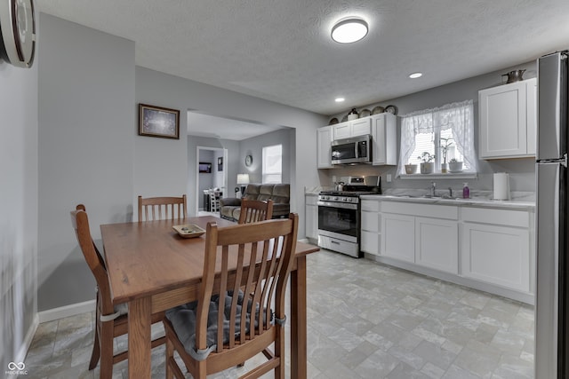 kitchen featuring stainless steel appliances, sink, white cabinets, and a textured ceiling