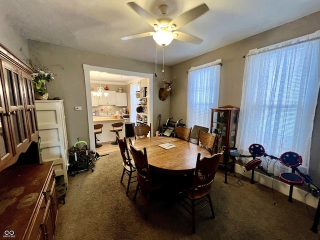 carpeted dining area featuring sink and ceiling fan with notable chandelier