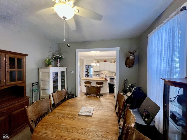 dining area featuring ceiling fan with notable chandelier