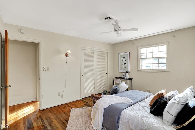 bedroom featuring baseboards, visible vents, a ceiling fan, dark wood-style flooring, and a closet