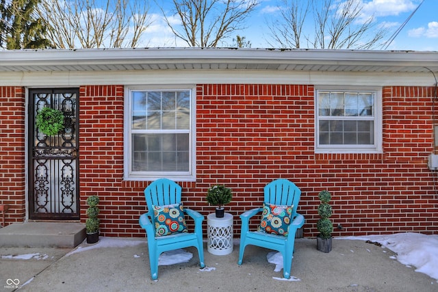 property entrance with brick siding and a patio