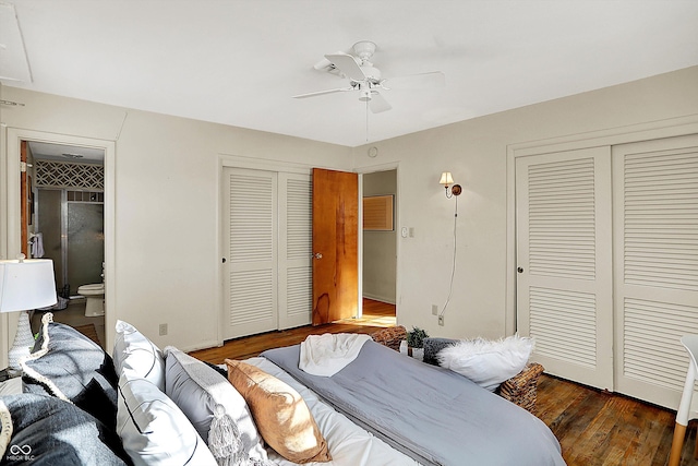 bedroom with a ceiling fan, dark wood finished floors, ensuite bathroom, and two closets