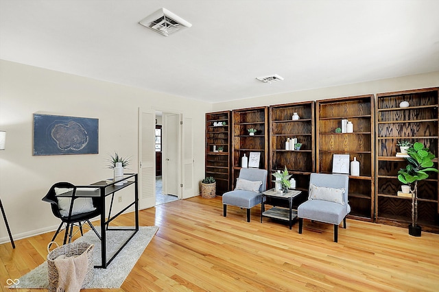 living area featuring light wood-style floors, visible vents, and baseboards