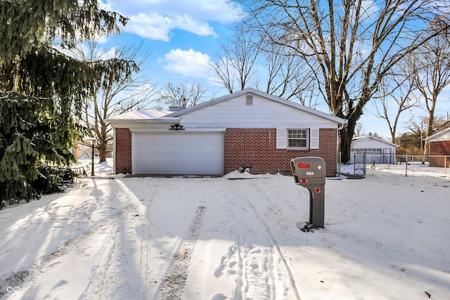 view of snow covered exterior featuring brick siding, fence, and an attached garage