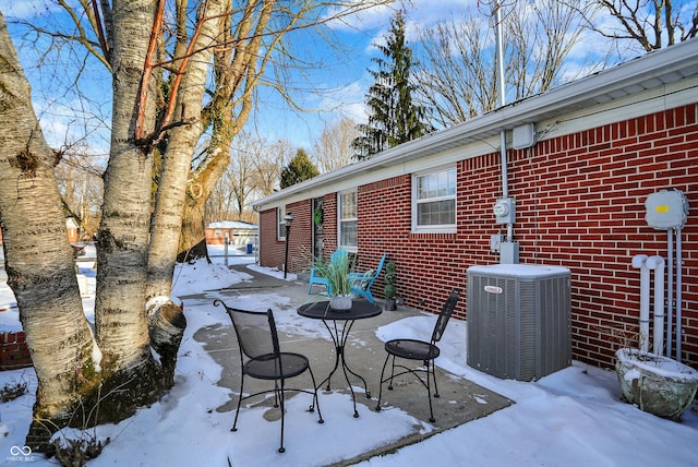 snow covered patio featuring central AC unit