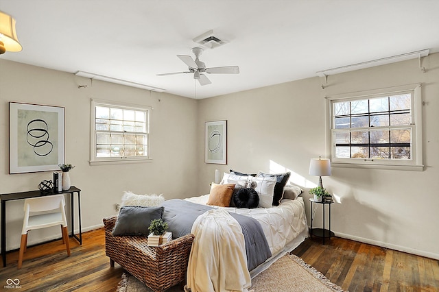 bedroom with ceiling fan, dark wood finished floors, visible vents, and baseboards