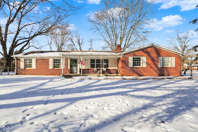 ranch-style home with a porch, brick siding, and a chimney