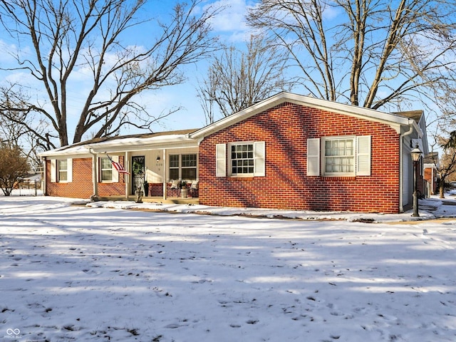 single story home featuring brick siding and a porch