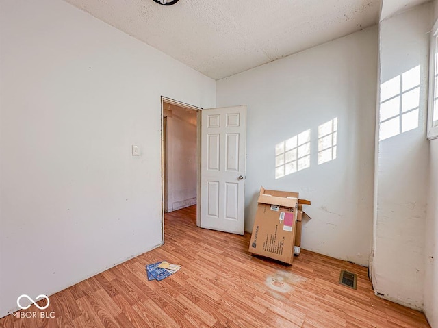 interior space with a textured ceiling and light hardwood / wood-style flooring