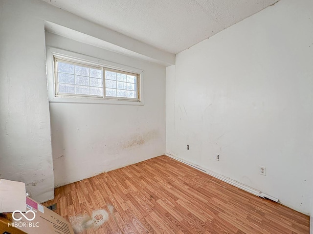 empty room with light hardwood / wood-style floors and a textured ceiling