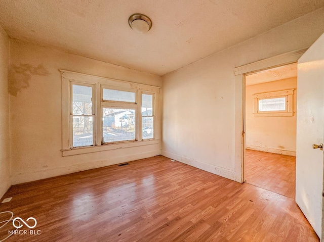 spare room featuring hardwood / wood-style flooring and a healthy amount of sunlight