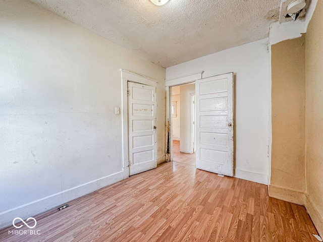 unfurnished bedroom featuring a textured ceiling and light hardwood / wood-style floors