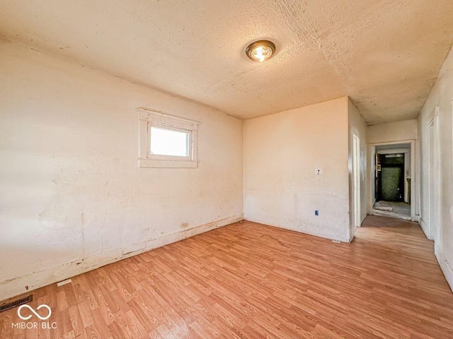 unfurnished room featuring light hardwood / wood-style floors and a textured ceiling