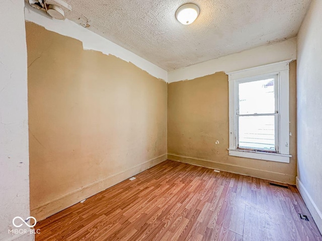 spare room featuring a textured ceiling and light wood-type flooring