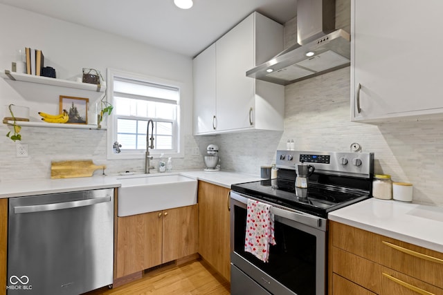 kitchen featuring sink, backsplash, stainless steel appliances, white cabinets, and wall chimney exhaust hood