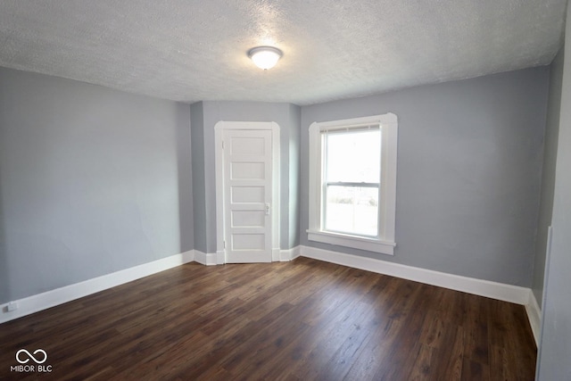 spare room featuring dark hardwood / wood-style floors and a textured ceiling