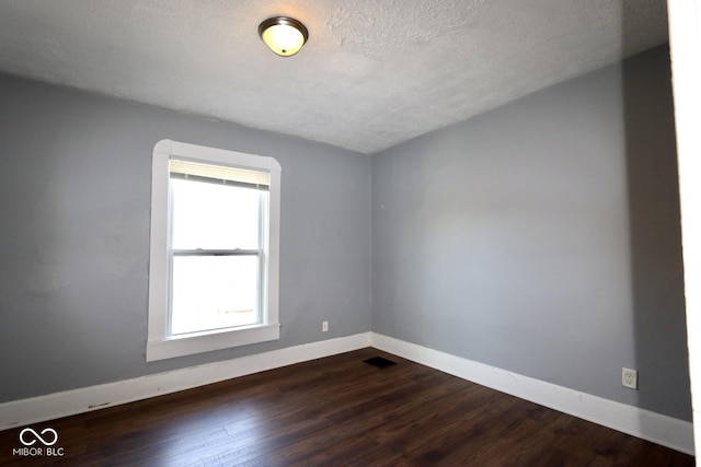 unfurnished room with dark wood-type flooring and a textured ceiling