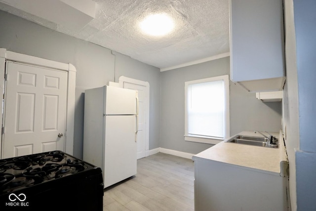 kitchen with sink, light hardwood / wood-style flooring, gas stove, a textured ceiling, and white fridge