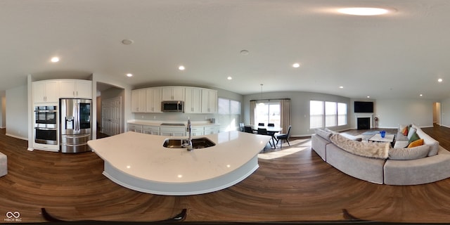 kitchen with sink, dark wood-type flooring, stainless steel appliances, and an island with sink