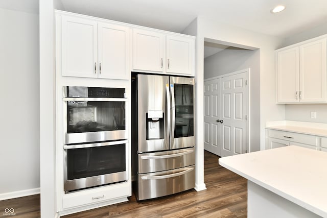 kitchen with stainless steel appliances, white cabinetry, and dark hardwood / wood-style flooring