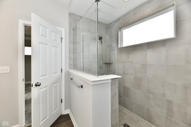 bathroom featuring a tile shower and wood-type flooring