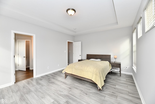 bedroom with a tray ceiling and light hardwood / wood-style flooring