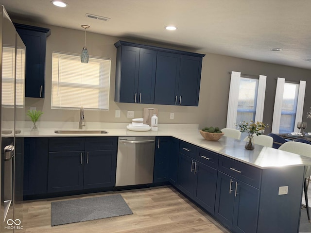 kitchen featuring blue cabinets, sink, hanging light fixtures, stainless steel dishwasher, and kitchen peninsula