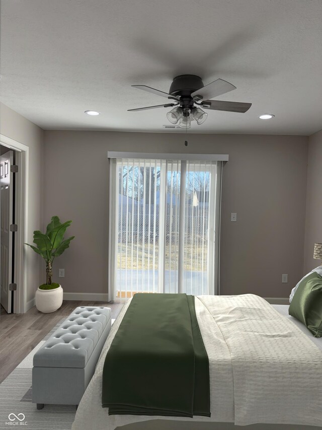 bedroom with multiple windows, hardwood / wood-style flooring, access to outside, and ceiling fan