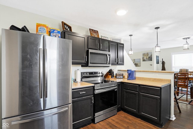 kitchen featuring stainless steel appliances, hanging light fixtures, dark wood-type flooring, and kitchen peninsula