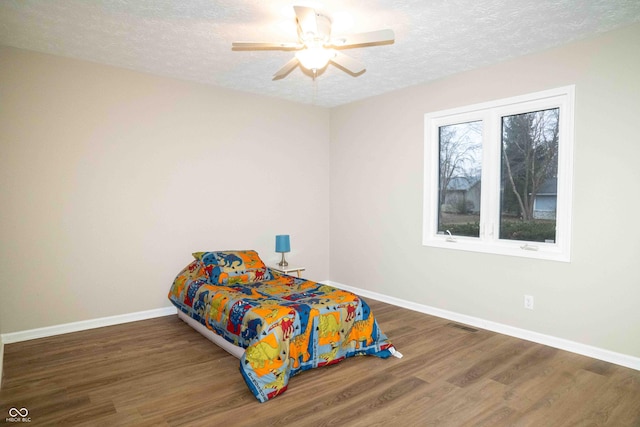 bedroom featuring ceiling fan, a textured ceiling, and dark hardwood / wood-style flooring