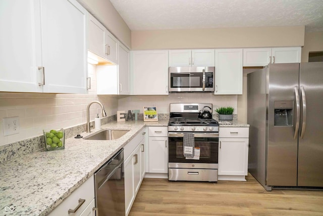 kitchen with sink, stainless steel appliances, light hardwood / wood-style floors, and white cabinets