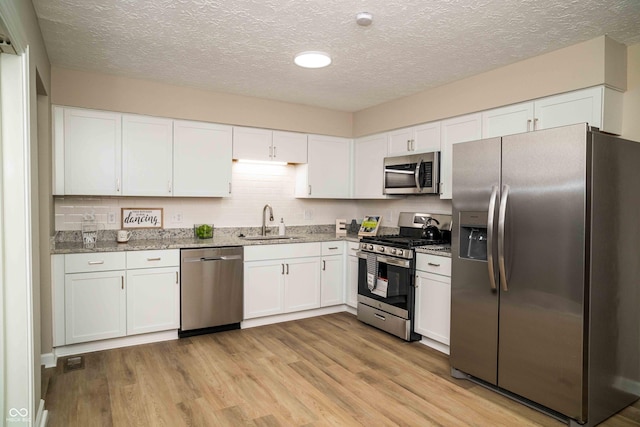 kitchen featuring stainless steel appliances, light hardwood / wood-style floors, sink, and white cabinets