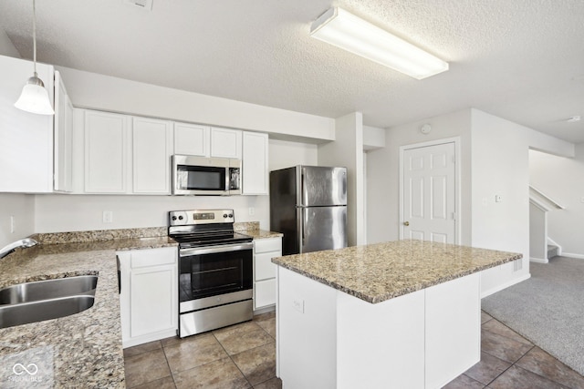 kitchen with stainless steel appliances, white cabinetry, hanging light fixtures, and sink