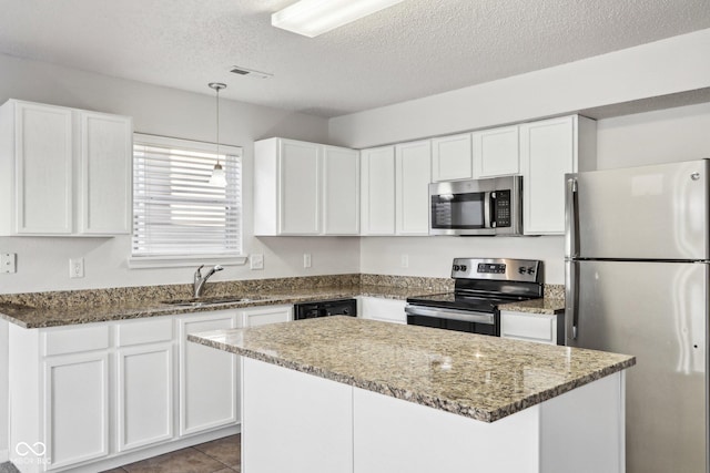 kitchen with sink, white cabinetry, stone countertops, a center island, and appliances with stainless steel finishes