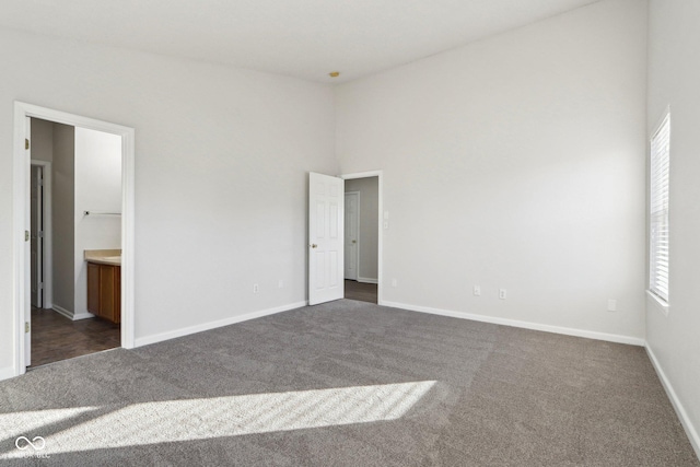 unfurnished bedroom with dark colored carpet and ensuite bathroom