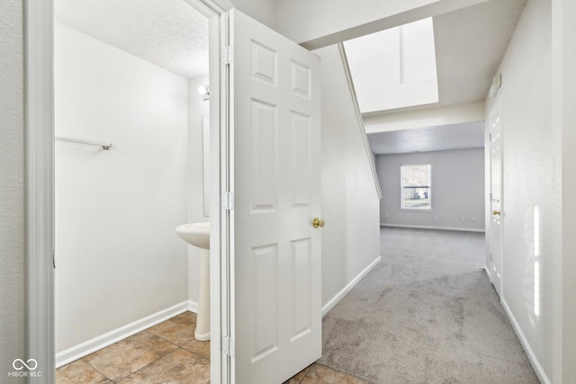 corridor with light colored carpet and a textured ceiling