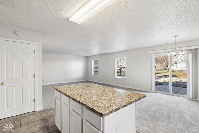 kitchen featuring a center island, light carpet, a chandelier, and decorative light fixtures