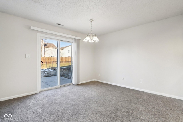 carpeted spare room featuring a notable chandelier and a textured ceiling