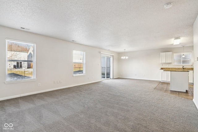 unfurnished living room featuring an inviting chandelier, sink, light carpet, and a textured ceiling