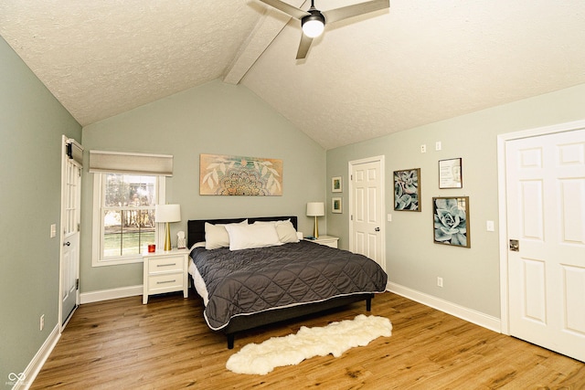 bedroom with vaulted ceiling with beams, ceiling fan, a textured ceiling, and light wood-type flooring