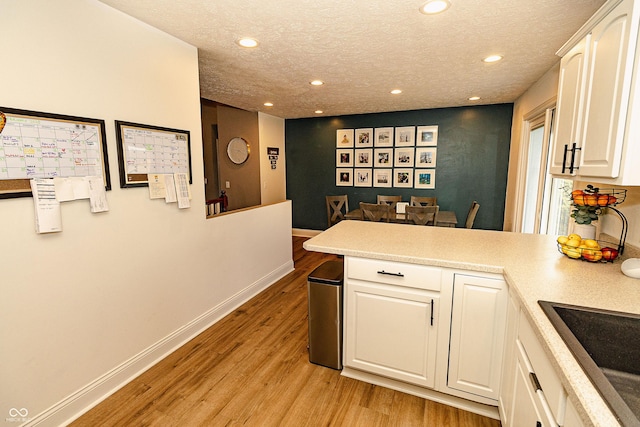 kitchen featuring white cabinetry, sink, a textured ceiling, and light hardwood / wood-style floors