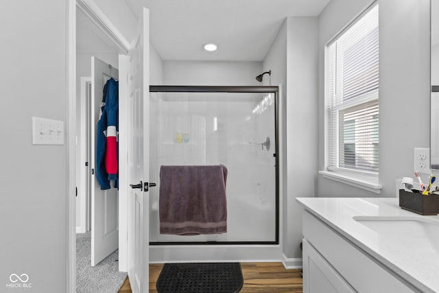 bathroom with walk in shower, vanity, and wood-type flooring