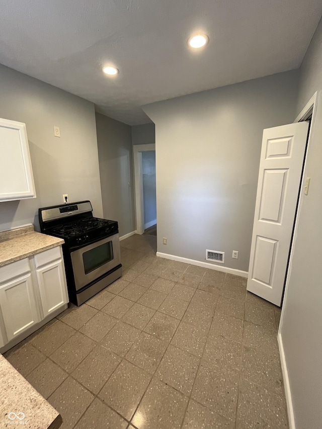 kitchen featuring stainless steel range with gas cooktop and white cabinets