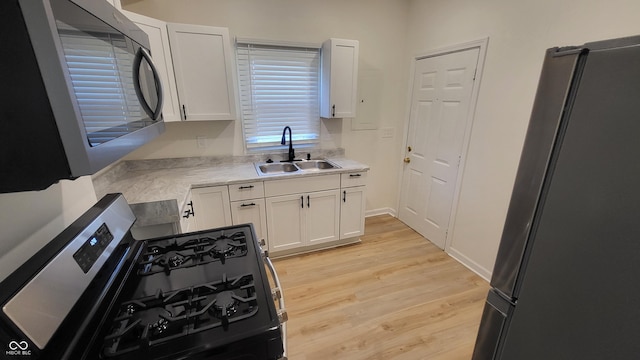 kitchen featuring white cabinetry, stainless steel appliances, sink, and light hardwood / wood-style flooring