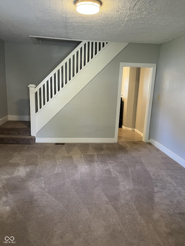 stairway featuring a textured ceiling and carpet flooring