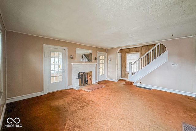 unfurnished living room with carpet floors, a brick fireplace, and a textured ceiling