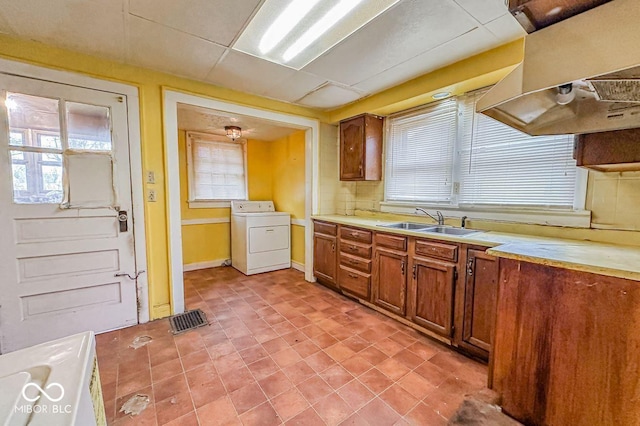 kitchen featuring extractor fan, washer / dryer, sink, and a drop ceiling