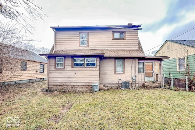 rear view of house with central AC unit and a lawn