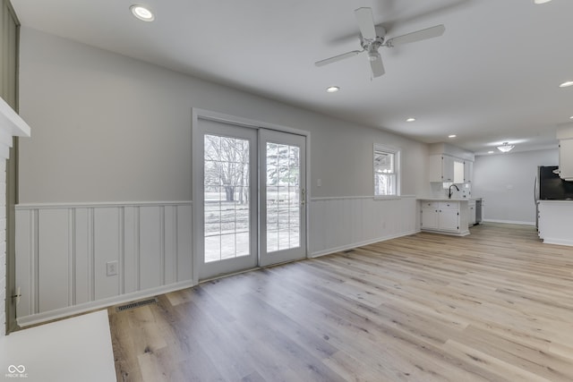 unfurnished living room featuring sink, ceiling fan, and light wood-type flooring