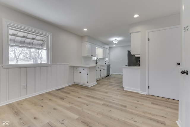 kitchen with sink, refrigerator, light hardwood / wood-style floors, white cabinets, and stainless steel dishwasher